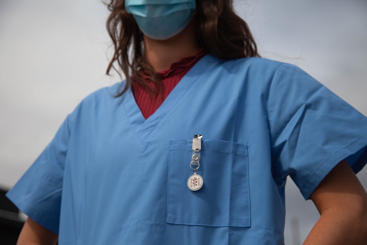 Profissional de saúde em scrub vermelho com óculos de proteção